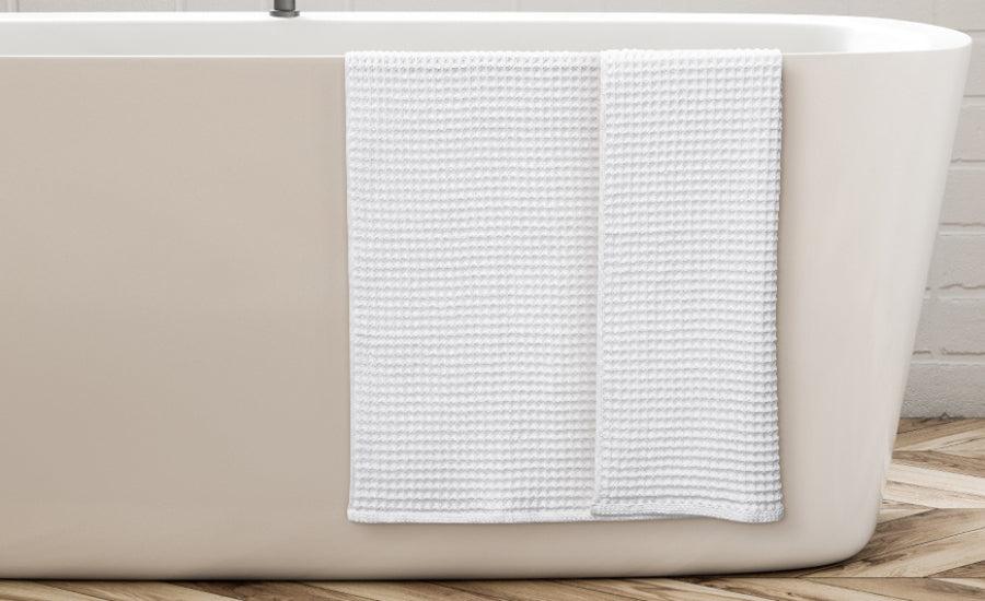 White Alusa Home Waffle Collection towel draped over a bathtub
