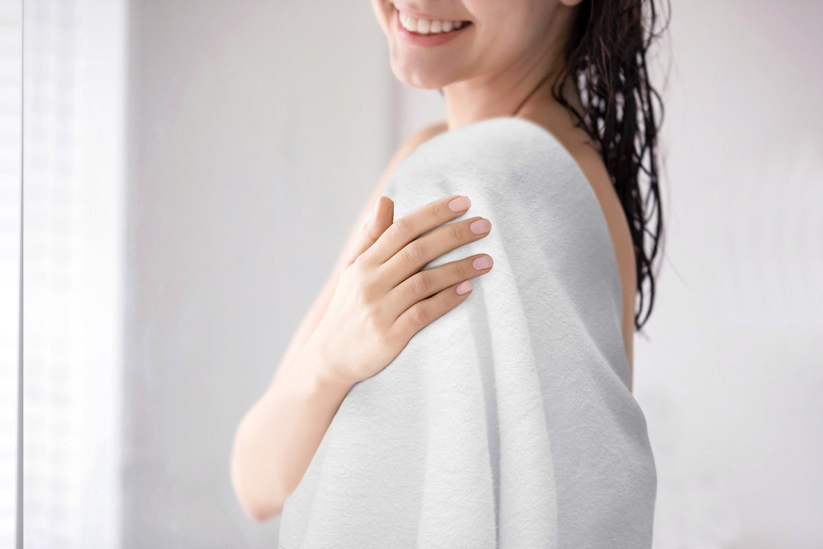 Soft white Alusa Home Bamboo Collection towel wrapped around a shoulder